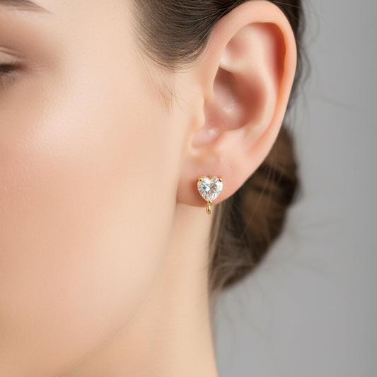 Close-up of a woman's ear wearing a heart-shaped earring against a neutral background