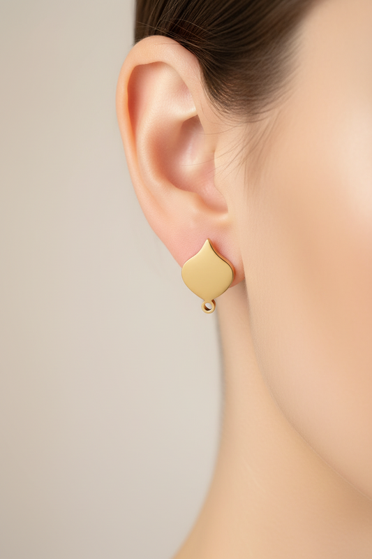 Gold earring worn by a person on a neutral background
