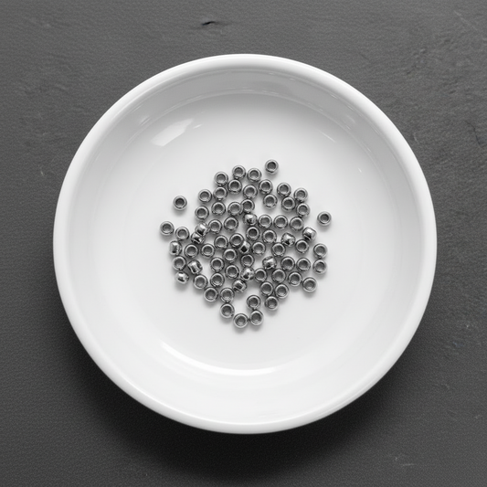 Small metal beads in a white bowl on a dark gray background
