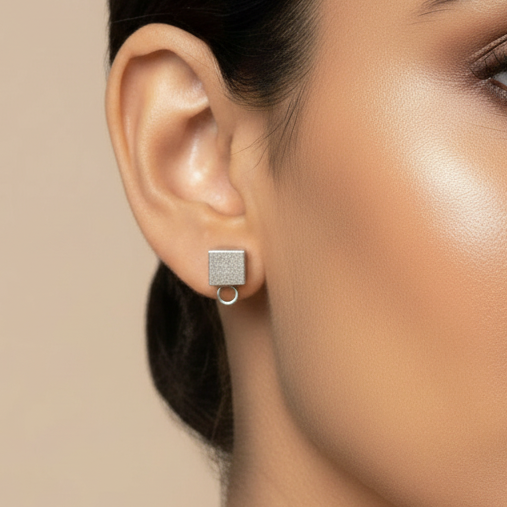 Close-up of a woman wearing a square earring against a beige background