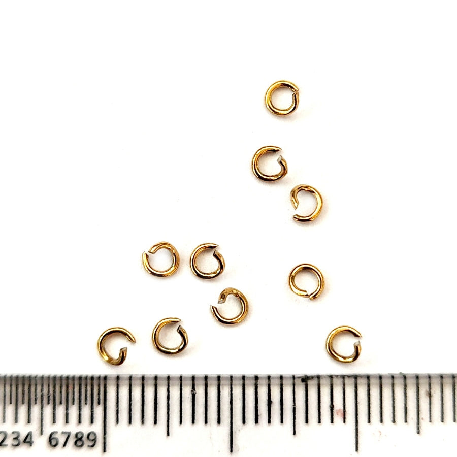 Gold jump rings with a ruler for scale on a white background
