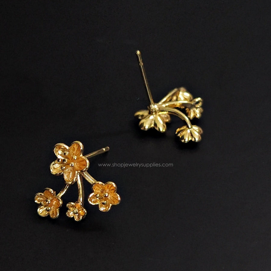 Pair of gold floral earrings on a black background
