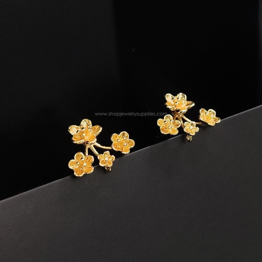 Gold floral earrings on a black background
