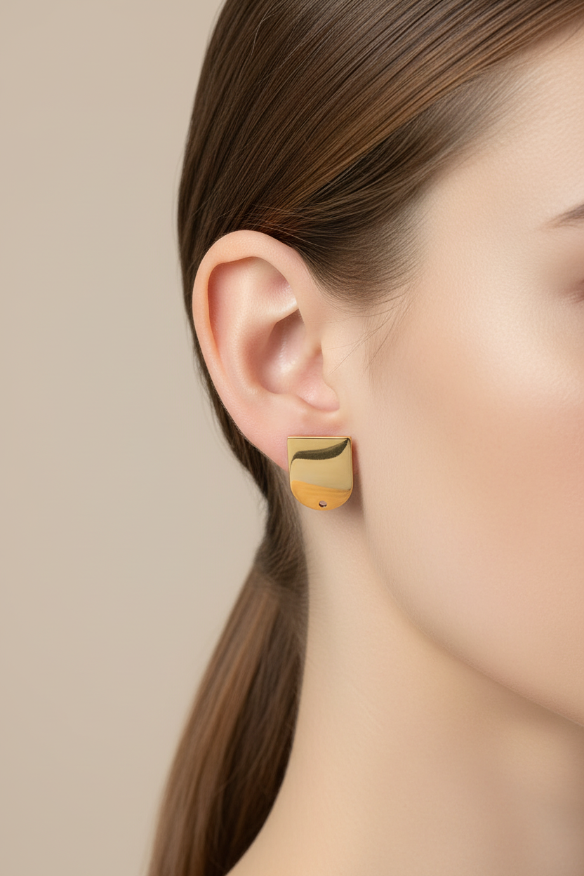 Gold earring worn by a model on a beige background
