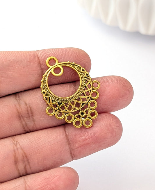 Gold filigree pendant held between fingers on a white background