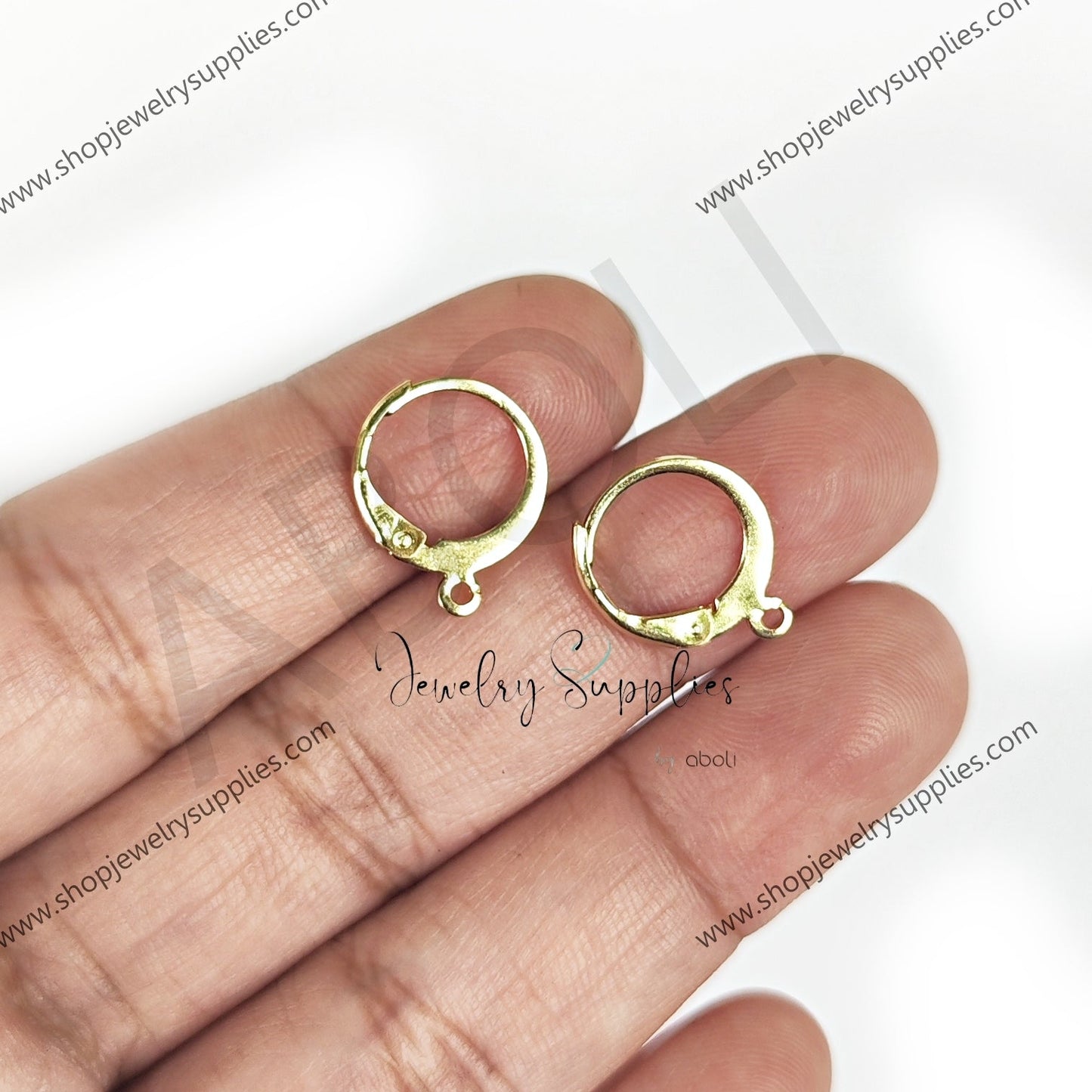 Gold hoop earrings held between fingers on a white background with 'shopjewelrysupplies.com' branding.