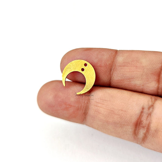 Gold crescent moon connector held between fingers on a white background