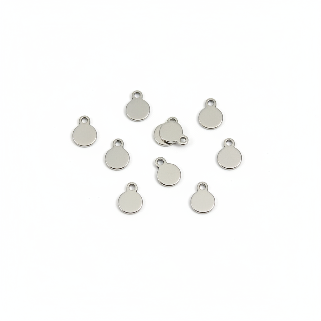 A tiny silver oval charm with a small loop at the top, resting on a person's fingertips against a plain white background.