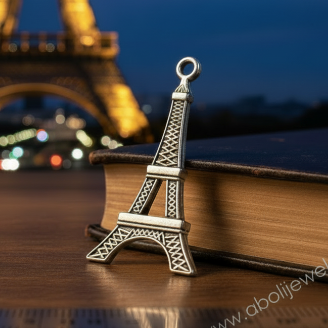 Small Eiffel Tower model on a book with the Eiffel Tower in the background at night.