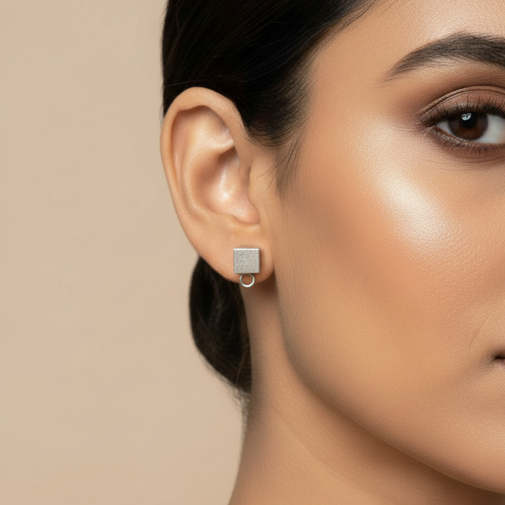 Close-up of a woman wearing a square earring against a beige background
