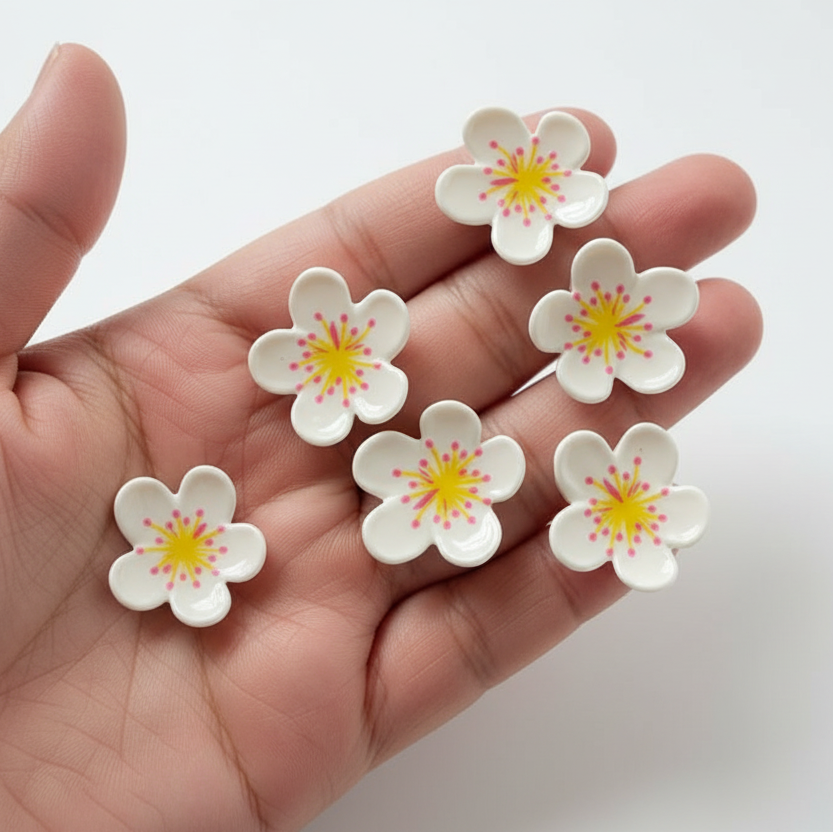 Hand holding six white flowers with yellow centers on a light gray background