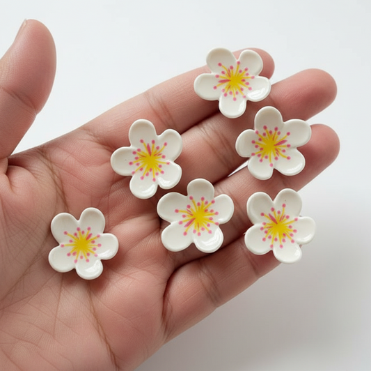 Hand holding six white flowers with yellow centers on a light gray background