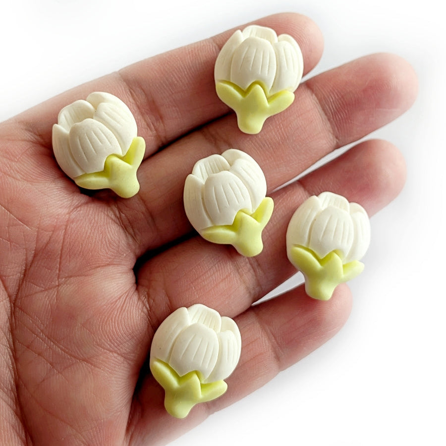 White and yellow flower-shaped cabochons on a hand against a white background