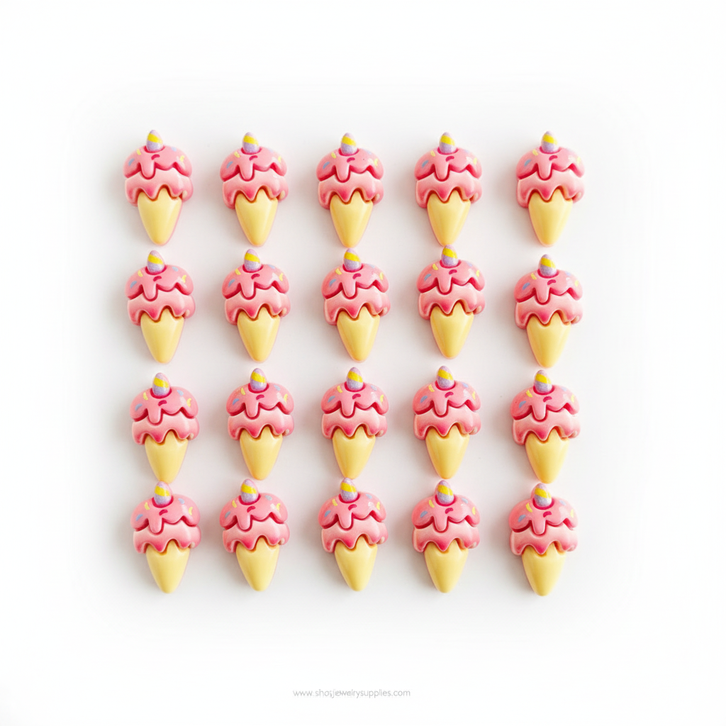 Ice cream cone-shaped resin cabochons with pink tops and yellow bases held in a hand on a white background