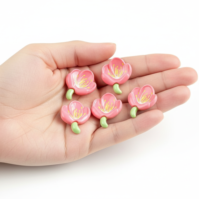 Hand holding pink flower-shaped objects with green stems on a white background