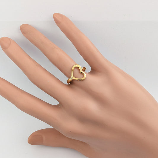 Gold heart-shaped ring on a mannequin hand against a white background