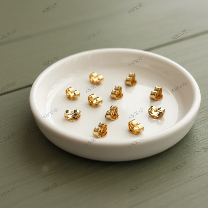 Gold earrings on a white dish on a wooden surface