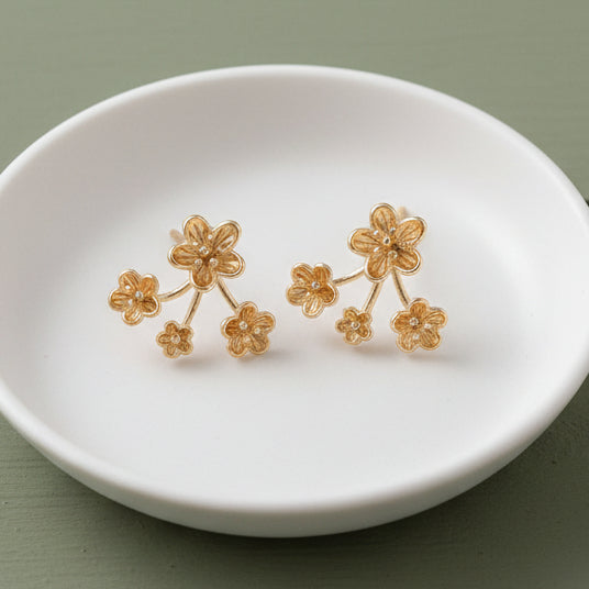 Pair of gold floral earrings on a light gray background