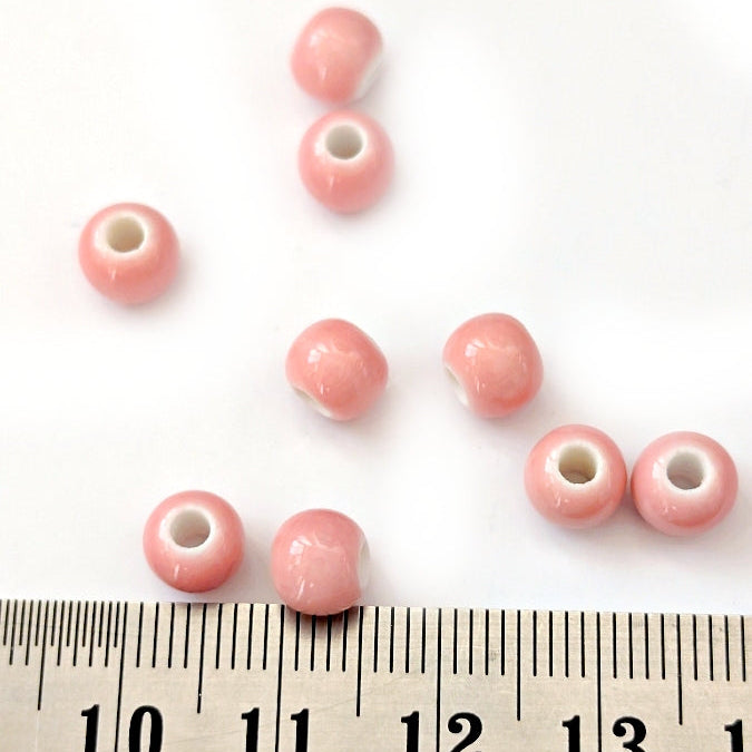Pink beads on a white background with a ruler for scale.