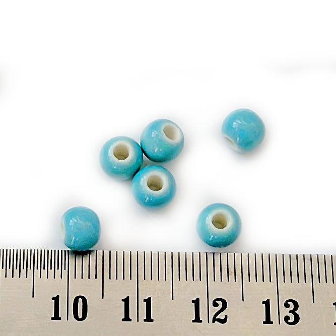 Blue beads with white centers on a white background with a ruler for scale.