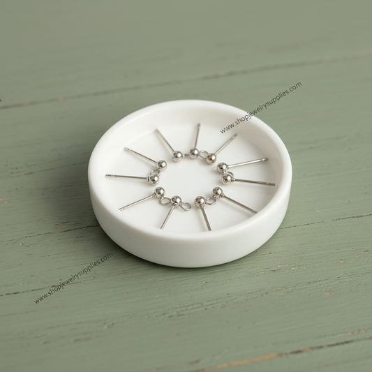 steel earring studs on a white dish with a green background